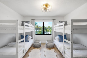 Generously sized guest bedroom offers flexible sleeping accommodations and a large window overlooking the tropical surroundings.
