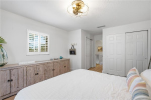 Another view of the primary bedroom highlights generous closet space, plantation shutters, and a clean coastal design.
