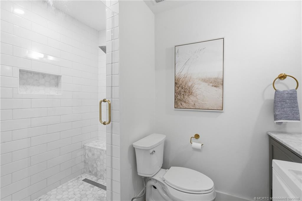 Updated walk-in shower features crisp subway tile, a decorative tile floor, built-in niche, bench, and glass enclosure.