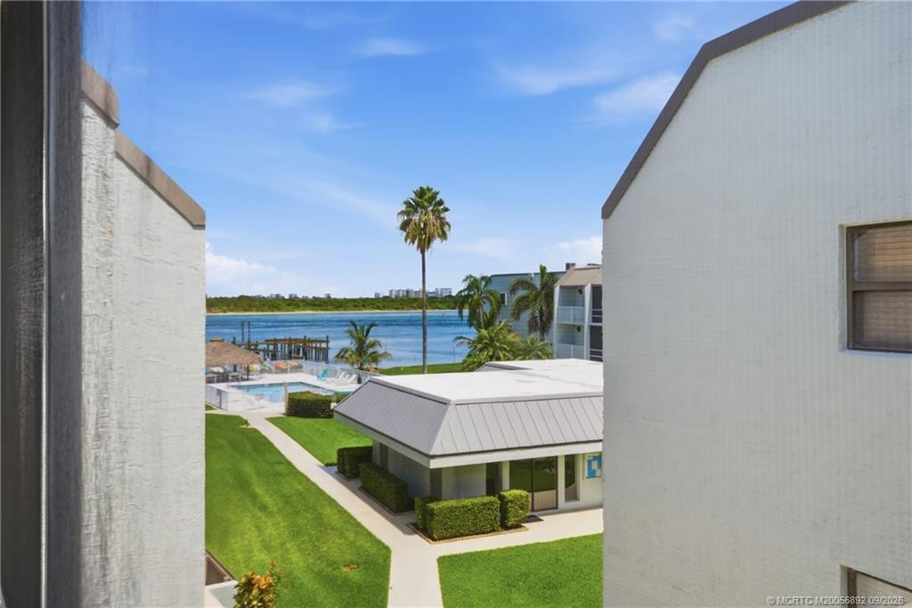 Elevated view toward the community pool and surrounding water, framed by tropical landscaping.