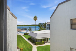 Elevated view toward the community pool and surrounding water, framed by tropical landscaping.