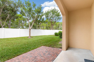 Fenced grassy common area adjacent to open-air brick paver patio which extends seating area of covered patio