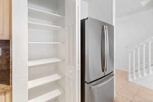 Newly installed adjustable solid shelving in pantry next to brand new GE French-door stainless-steel refrigerator