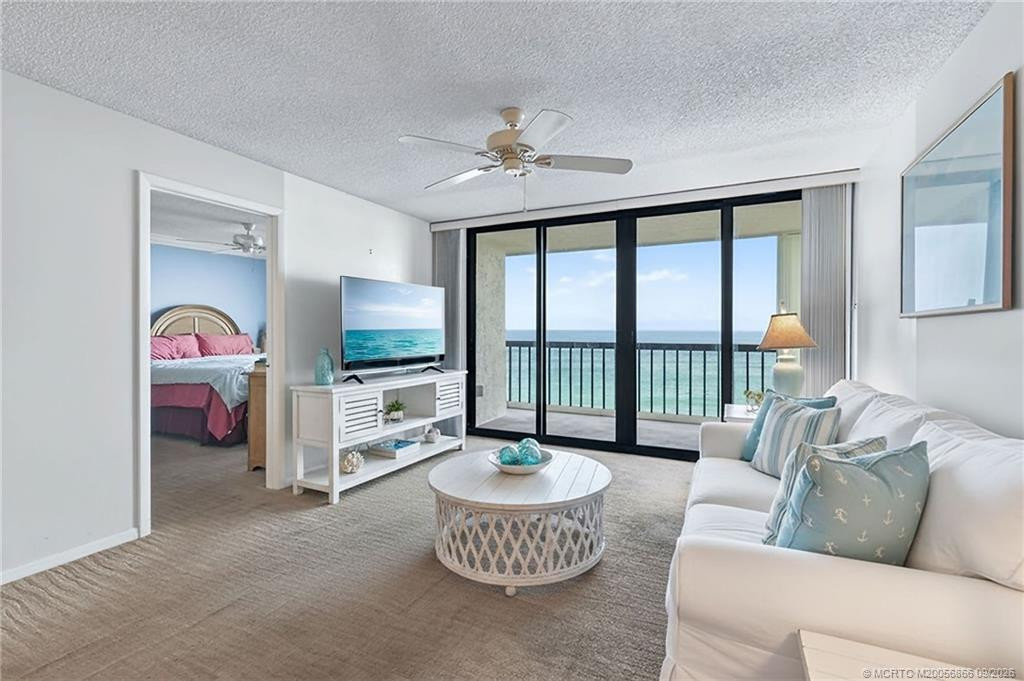 Living room with expansive glass doors framing beautiful direct ocean views and access to the private balcony. Virtually staged.