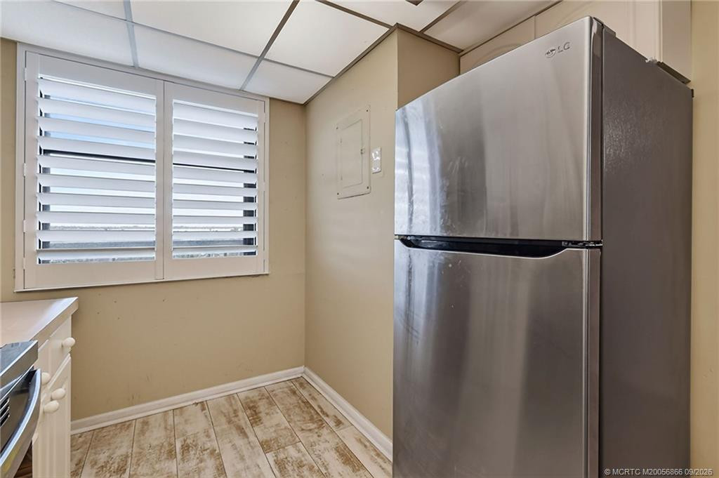 Additional kitchen view with stainless steel refrigerator and plantation shutters.