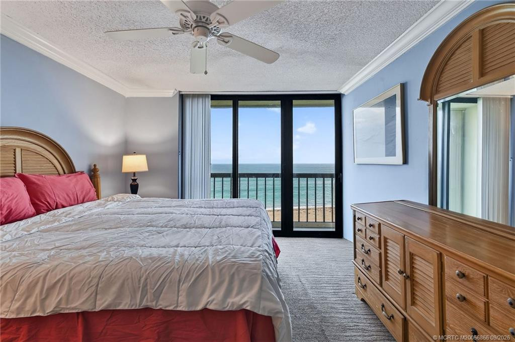Wake up to the ocean from the spacious primary bedroom with floor-to-ceiling glass doors and balcony access.
