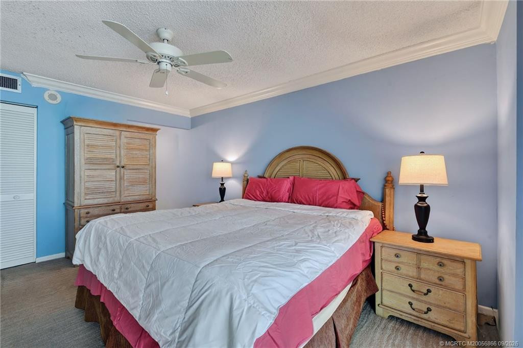 Spacious primary bedroom with crown molding, ceiling fan and ample room for a king-size bed.
