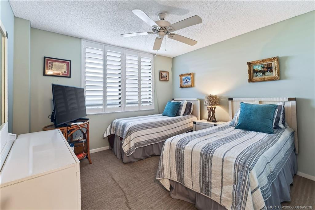 Guest bedroom with twin beds, ceiling fan and plantation shutters.