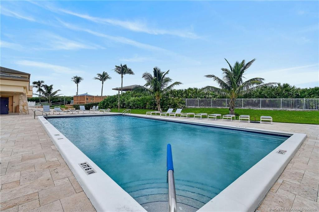 Community swimming pool surrounded by a spacious pool deck and tropical landscaping.
