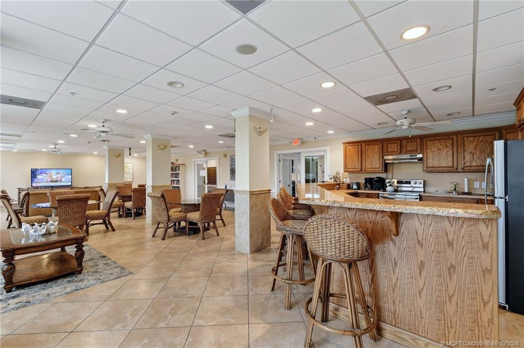 Additional view of the community social room featuring a full kitchen, bar seating and gathering space.