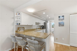 Open kitchen features granite countertops, white cabinetry and a spacious breakfast bar with seating.
