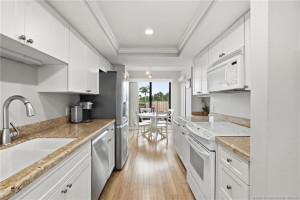 Bright galley-style kitchen with white cabinetry, granite countertops and stainless-steel appliances.
