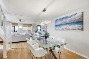 Open-concept dining area with wood flooring and ocean views extending through the adjacent living room.