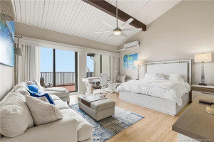 Expansive oceanfront primary suite with soaring vaulted ceilings, exposed beams, sitting area and direct balcony access.