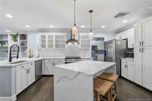 Beautifully appointed kitchen featuring crisp white cabinetry, generous counterspace, stainless steel appliances, and an island
