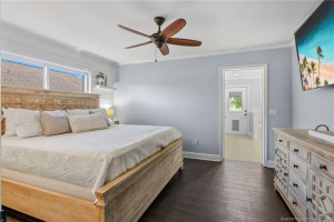 Relax in the spacious primary suite featuring wood-look flooring, soft neutral tones, and a calming coastal atmosphere.
