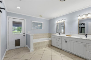 Spacious primary bath with double vanities, a soaking tub, and convenient access to the outdoor living areas.