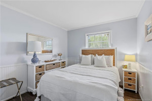 Comfortable guest bedroom featuring soft coastal tones, wood-look flooring