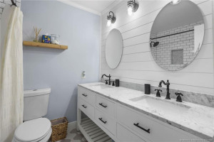 Guest bathroom with double sinks, countertops, black fixtures, and coastal-inspired shiplap accents
