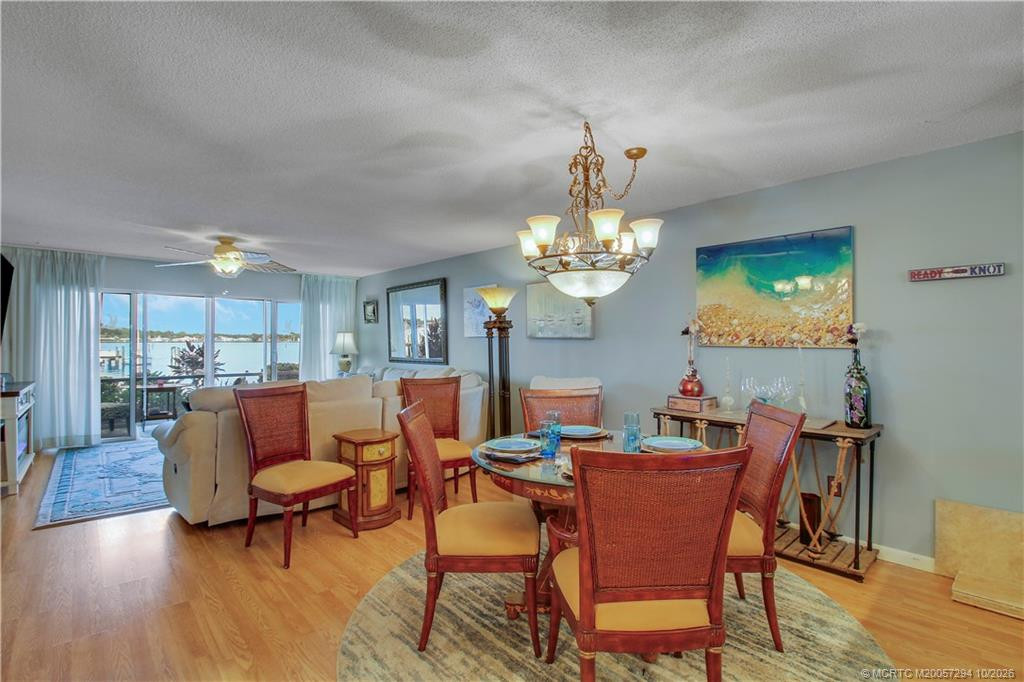 Enjoy waterfront views from the dining area! This inviting space features an elegant chandelier, coastal-inspired colors, and an open layout connecting the dining and living areas, perfect for entertaining family and friends.