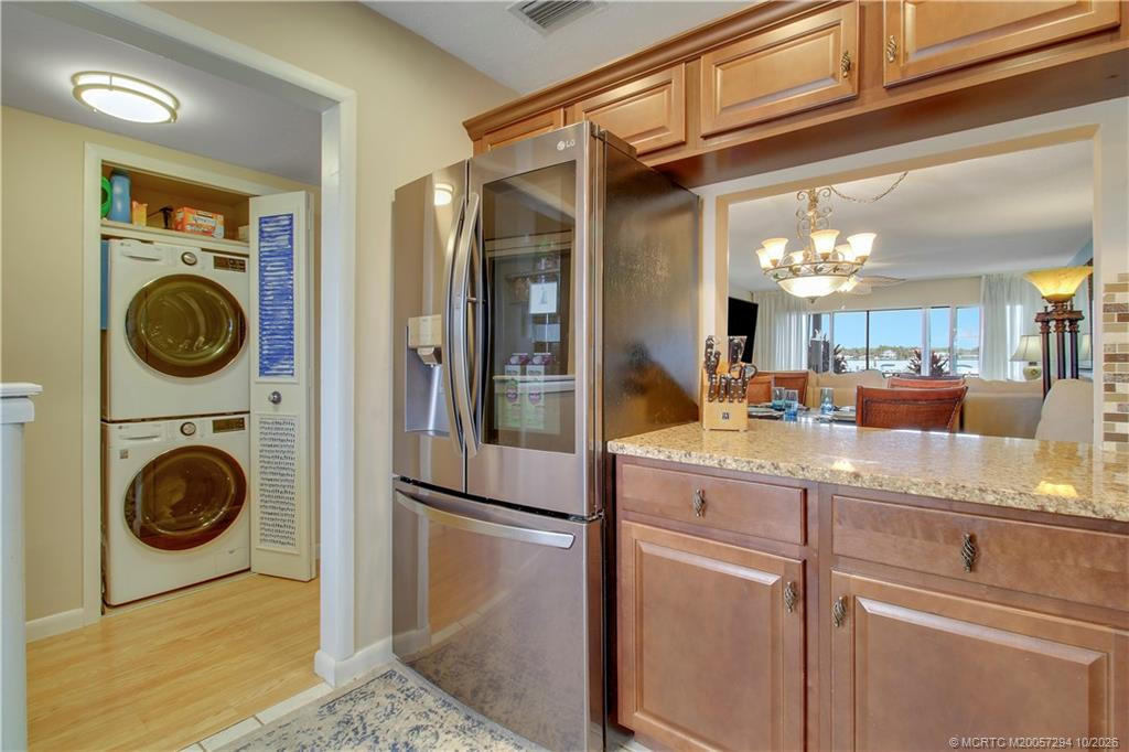 Beautifully appointed kitchen featuring warm wood cabinetry, granite countertops, and an LG stainless steel French-door refrigerator with glass-view panel. Convenient laundry closet with full-size stacked LG washer and dryer.