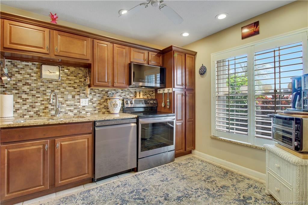 Natural light fills the kitchen through a large window with plantation shutters, offering pleasant views of tropical landscaping. A lovely finishing touch to this inviting space.