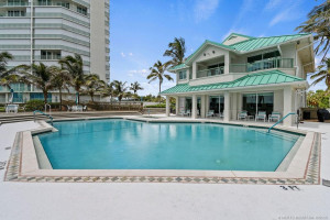 Beautiful resort-style pool area featuring a convenient poolside building with indoor facilities, restrooms, and an outdoor shower.