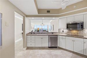Open kitchen with granite countertops, stainless-steel appliances, and a convenient pass-through overlooking the oceanfront living area.