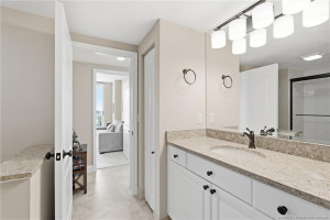 Additional view of the primary bathroom showcasing granite countertops, white cabinetry, and updated lighting.