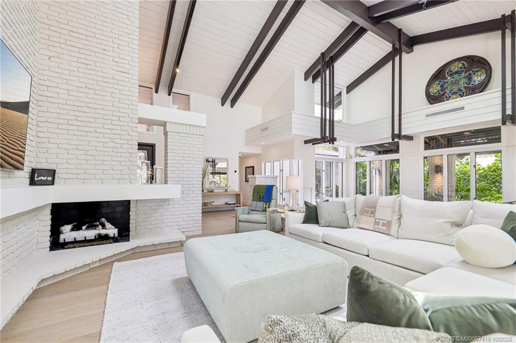 Soaring ceilings, exposed beams, and a white brick fireplace