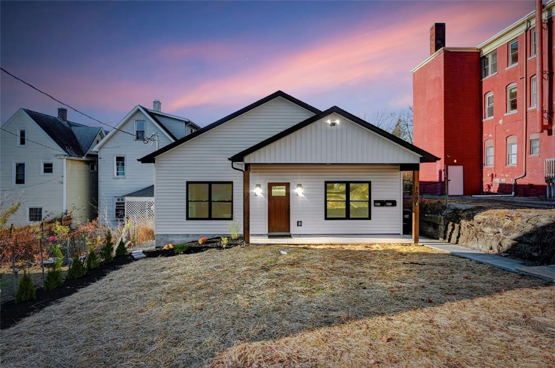 A quaint residence with light siding and dark trim, highlighted by the setting sun. A quaint residence with light siding and dark trim