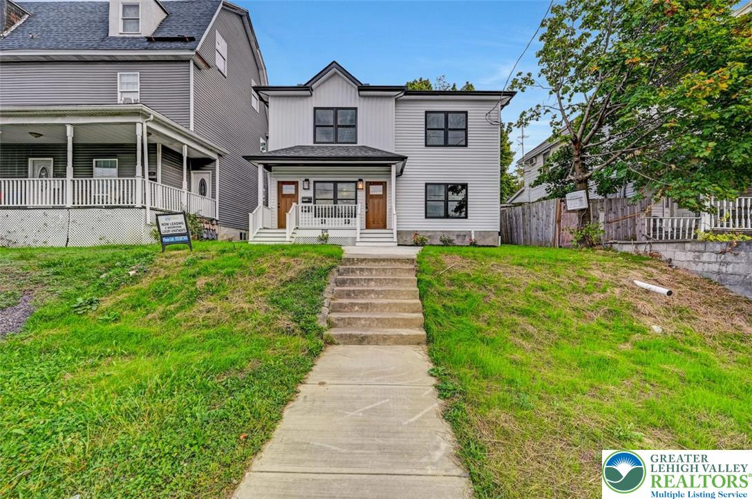 A newly constructed residence features a crisp white facade with dark trim, offering inviting twin front entrances. A newly constructed residence features a crisp whi