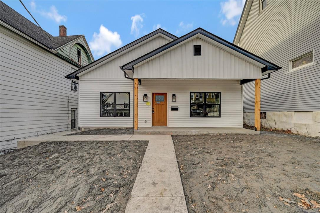 A newly constructed facade featuring a wood plank door and natural wood support columns welcomes you home. A newly constructed facade featuring a wood plank
