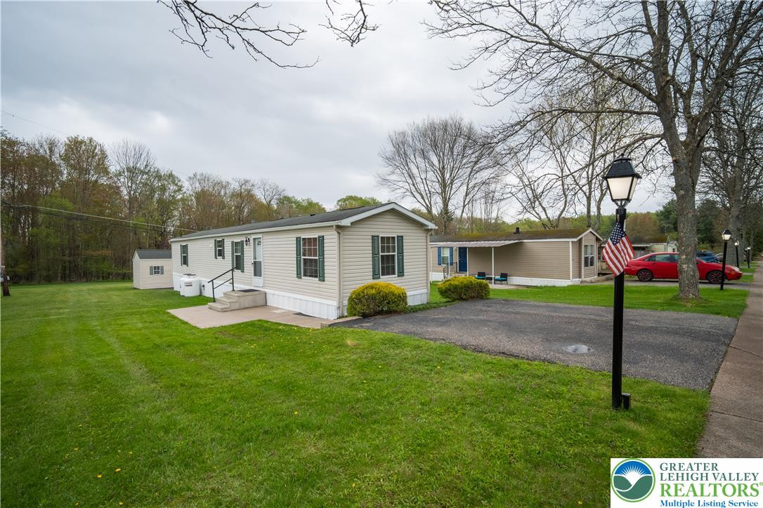 Mature trees frame a manicured green lawn surrounding this classic manufactured home. Mature trees frame a manicured green lawn surround