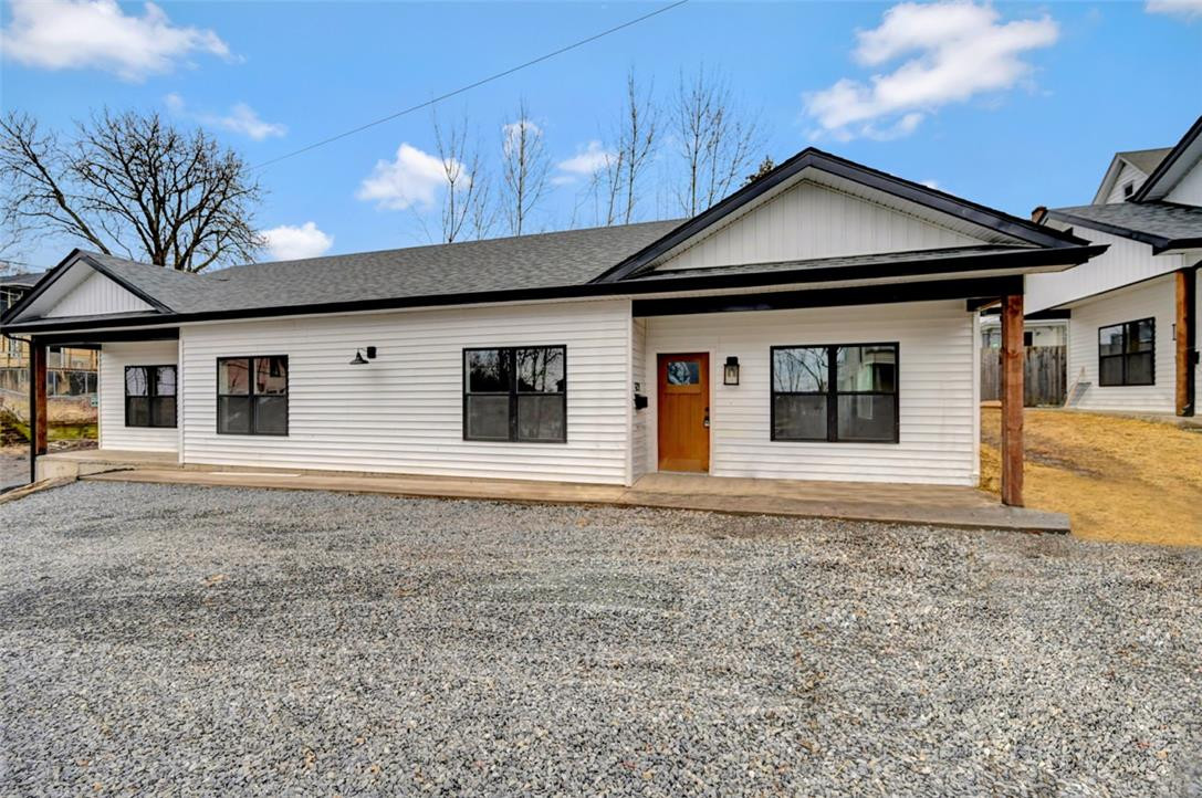 Modern façade with white siding and dark trim, highlighted by a natural wood entry door, defines this residence. Modern façade with white siding and dark trim, hig