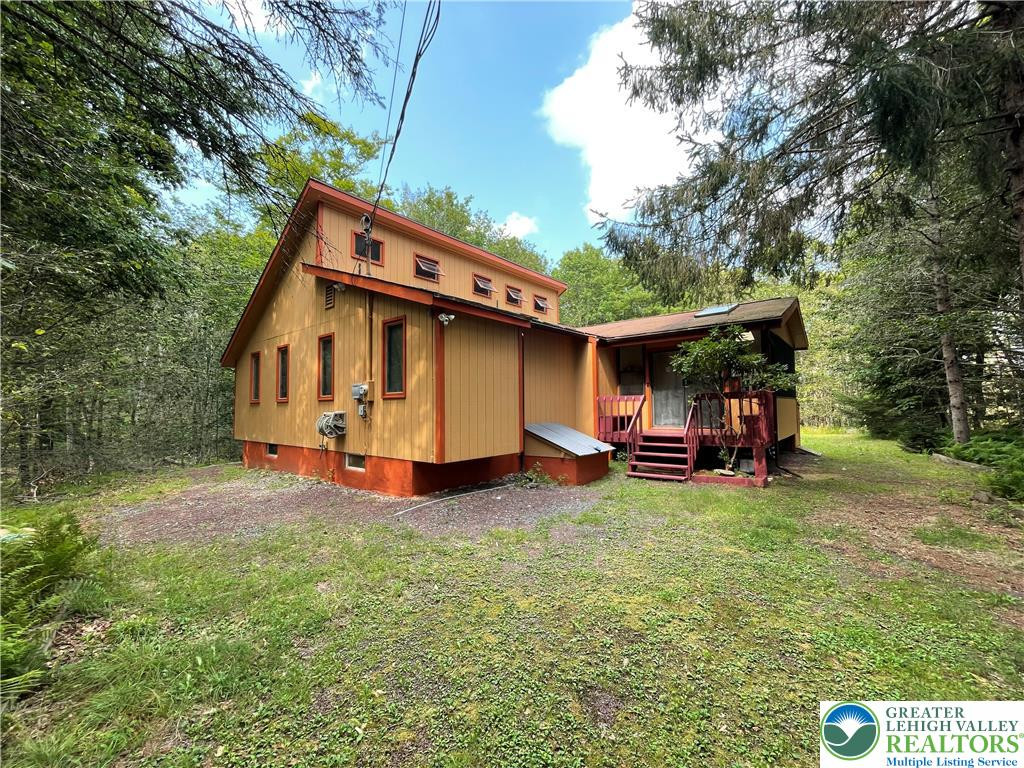 Mature trees frame a rustic wood-sided home featuring a raised foundation and multiple windows. Mature trees frame a rustic wood-sided home featur