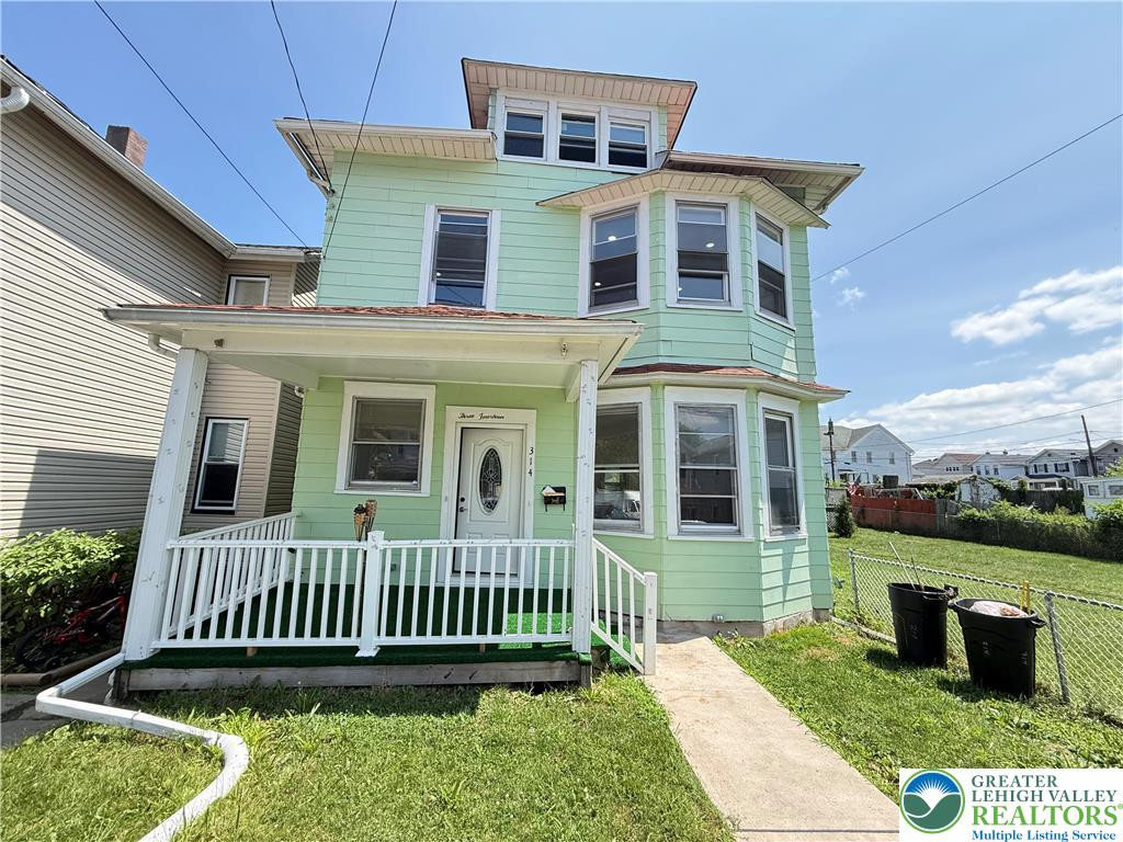 A charming three-story home with a welcoming front porch and a neatly fenced yard. A charming three-story home with a welcoming front