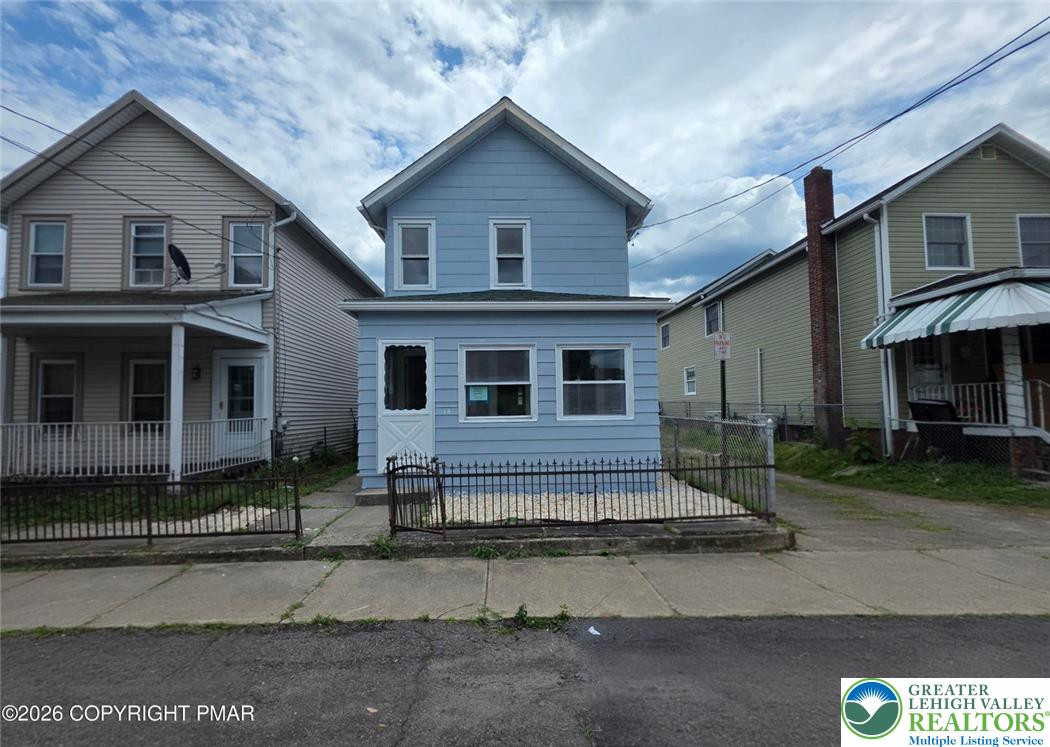 A classic two-story exterior showcases a defined front yard bordered by metal fencing. A classic two-story exterior showcases a defined f