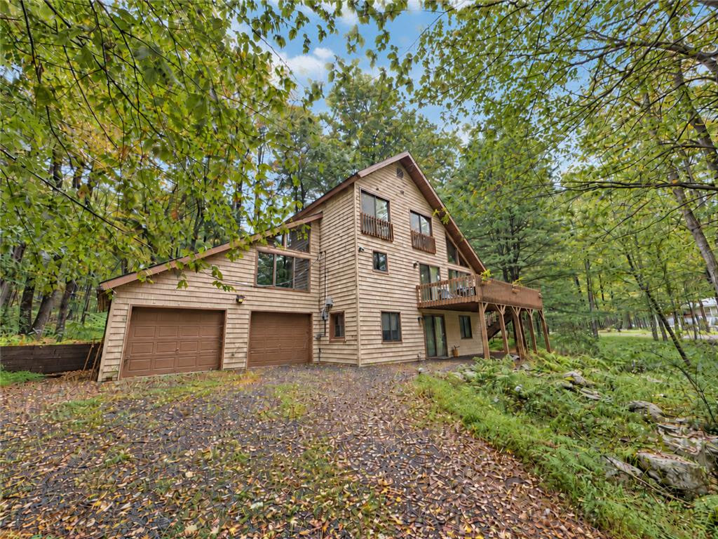 Mature trees frame a rustic wood-sided home featuring a private balcony and elevated deck. Mature trees frame a rustic wood-sided home featur