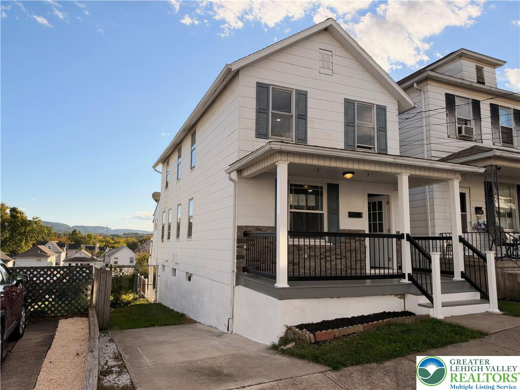 A welcoming front porch with classic columns and stone accents highlights this multi-story home. A welcoming front porch with classic columns and s