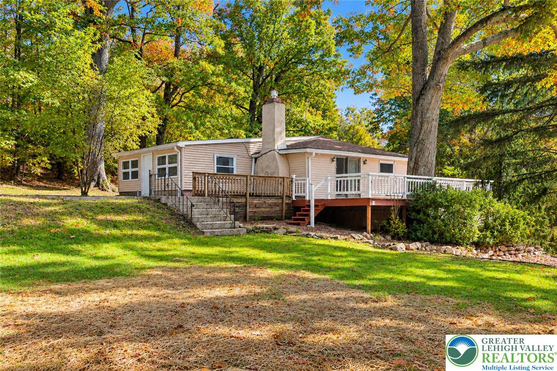 Mature trees frame a charming hillside home featuring multi-level decking and a brick fireplace chimney. Mature trees frame a charming hillside home featur