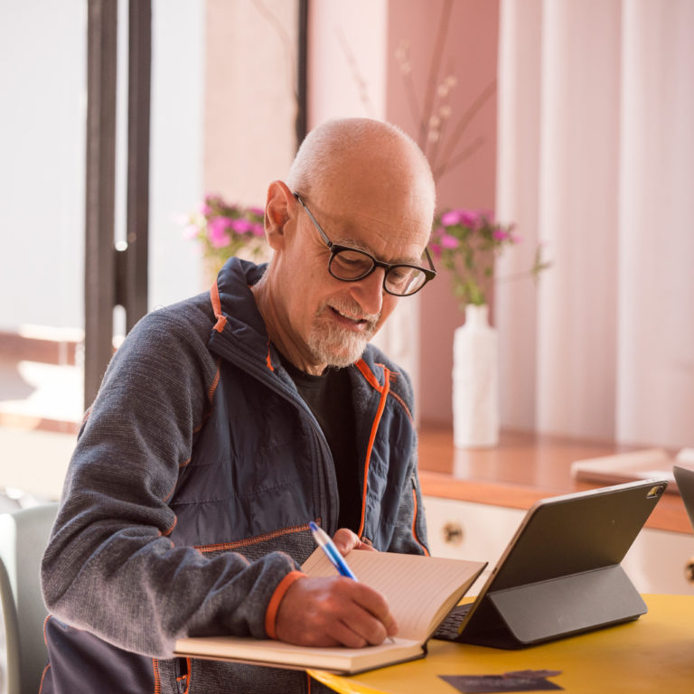 Adult learner engaged in a personalized Spanish lesson during Fluenz Live Online via Zoom, taking notes while working through the structured coaching program.