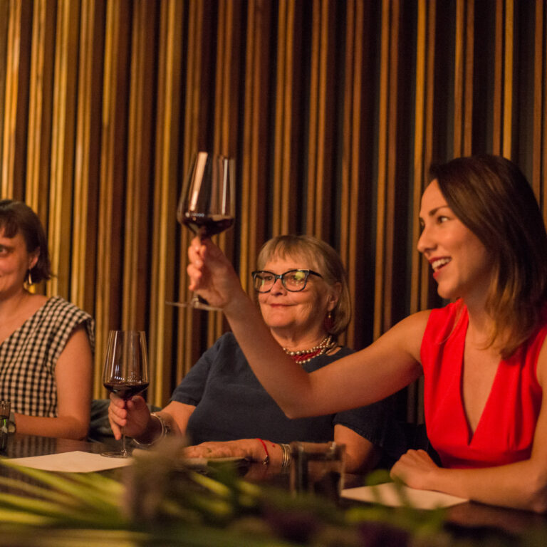 Adult learners enjoying a cultural evening during the Fluenz Spanish immersion program, toasting with wine in Mexico City.