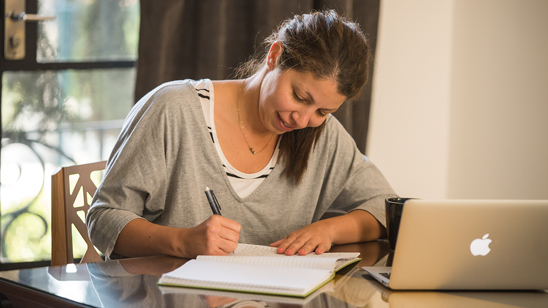Adult student participating in the Fluenz Online Spanish Immersion program, practicing writing exercises alongside personalized Spanish coaching on her laptop.
