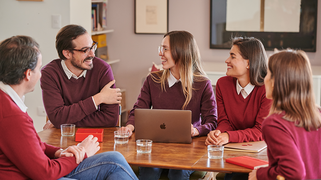 Spanish tutors in a team meeting, reviewing learner progress and dynamically adjusting lessons to provide a personalized, real-time language learning experience online.