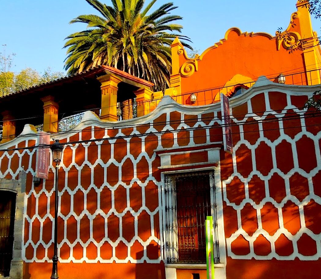 The National Sound Library in Mexico City, housed in a striking 18th-century red-and-white baroque building with tranquil gardens, one of the cultural landmarks experienced during the luxury Fluenz Spanish Immersion in Mexico City.