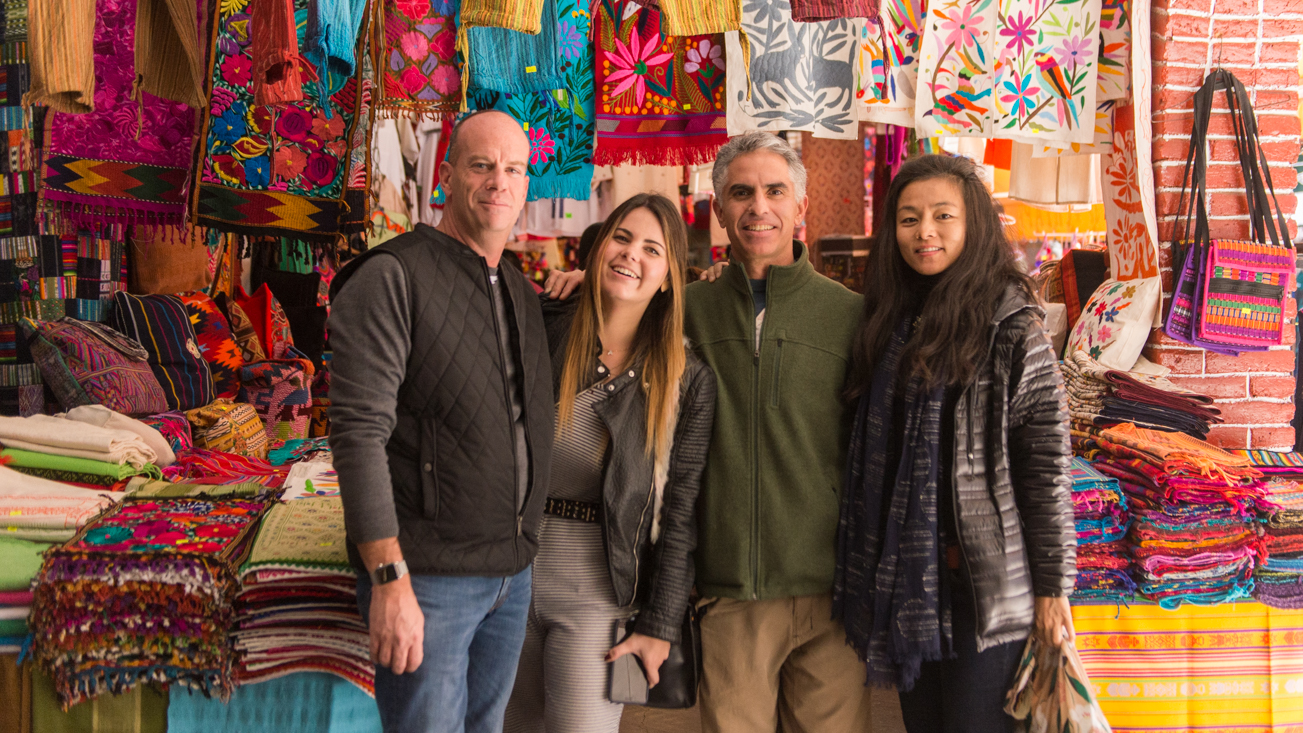 Fluenz Spanish Immersion learners in Mexico City practice Spanish while visiting a vibrant local market filled with handmade textiles and crafts.