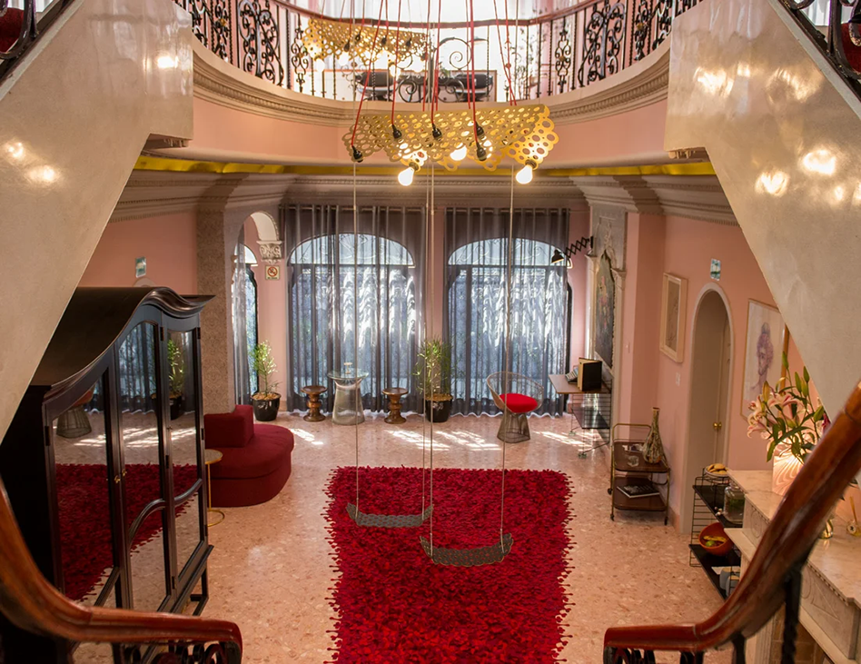 Elegant interior of the Polanco residence used for the Fluenz Spanish Immersion in Mexico City, featuring a grand staircase, designer lighting, and a red carpeted lounge where learners and coaches gather between personalized Spanish sessions.
