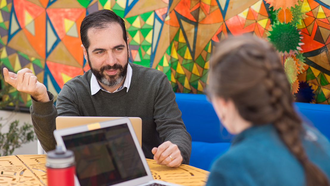 Spanish tutor and adult learner during a one-on-one session at the Fluenz Spanish Immersion in Mexico City, set against a colorful mosaic background that reflects the city’s vibrant artistic culture.