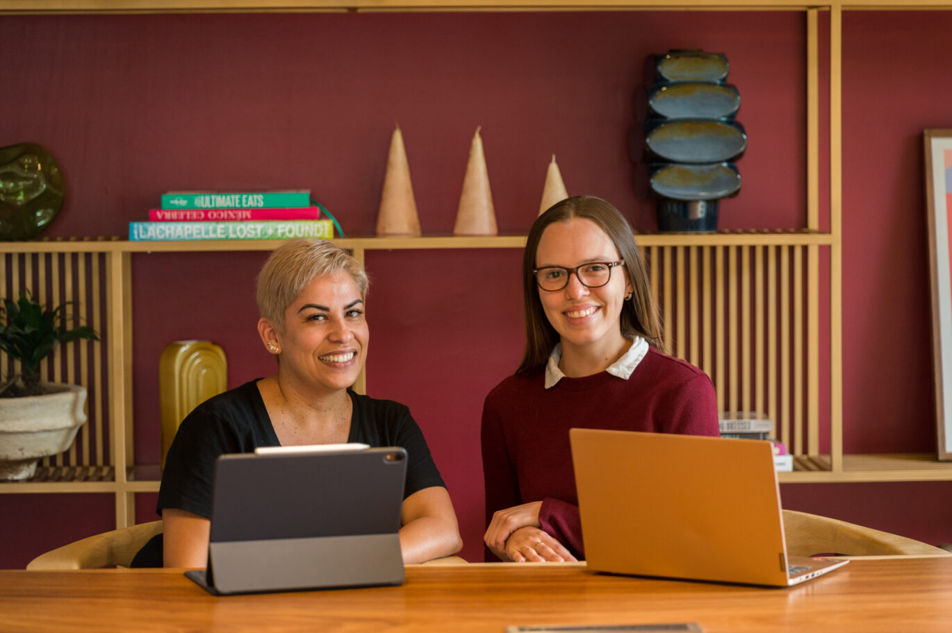 Spanish coach and adult learner during a personalized one-on-one session at the Fluenz Spanish Bootcamp in Mexico City. Both are seated at a modern table with laptops, smiling in a relaxed, elegant environment that reflects the immersive and high-end atmosphere of the program.